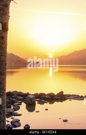 Tramonto su un lago tranquillo con riflessi e montagne circostanti, Grosser Alpsee, Immenstadt im Allgaeu, Baviera, Germania Foto Stock