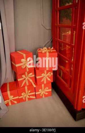 Scatole di cartone quadrate rosse per regali disposte su un piano studio. Concetto di festa di stagione, generosa donazione delle vacanze ed elegante confezione per l Foto Stock