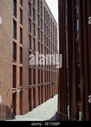 Moderni edifici in mattoni rossi fiancheggiano uno stretto vicolo nel quartiere di Rotterdam, Tallinn, Estonia, in una soleggiata giornata primaverile Foto Stock