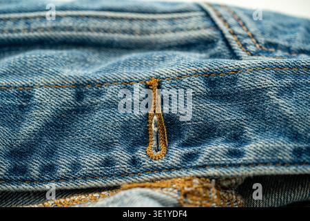 Primo piano con cucitura in denim e bottone. Foto Stock