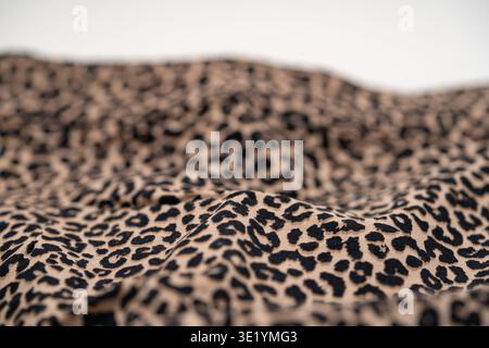 Primo piano della trama in tessuto con stampa leopardata con pieghe e motivi morbidi. Foto Stock