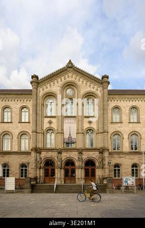 Edificio principale storico dell'Università di Göttingen in Germania, caratterizzato da un'elegante architettura neoclassica con un ciclista di passaggio in un vivace ur Foto Stock