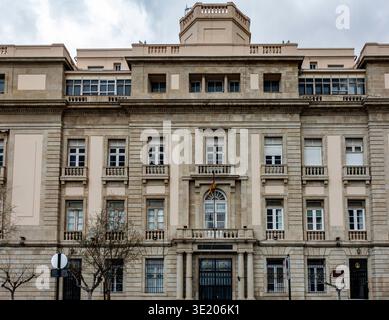 La facciata in pietra dell'edificio del governo militare di Cartagena, Spagna, presenta finestre simmetriche, un balcone centrale e una bandiera spagnola. Foto Stock