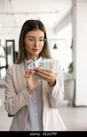 Giovane donna d'affari che usa lo smartphone in ufficio Foto Stock