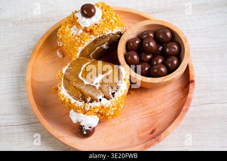 Due fette di torta arrotolata con panna montata e palline di cioccolato in Una ciotola Foto Stock