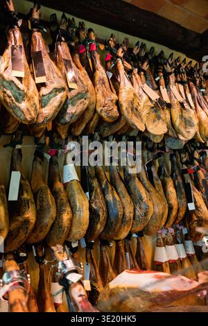 Fila di gambe pendenti con etichette sulla vetrina della macelleria Foto Stock