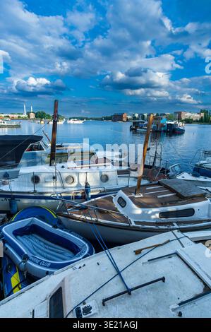 Vista verticale delle piccole barche ormeggiate sul lungomare di Rummelsburger Bucht a Berlino, con acque calme e spettacolari nuvole estive sopra la baia. Foto Stock