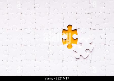 Una raccolta di pezzi del puzzle bianco è mostrata con un pezzo mancante Foto Stock