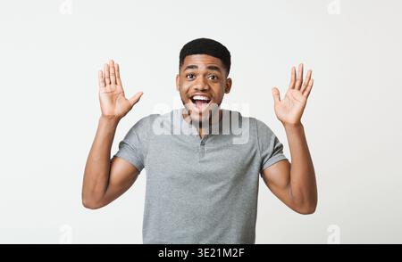 Sorpreso felice afro-americano tirando le mani verso la fotocamera per salutare Foto Stock