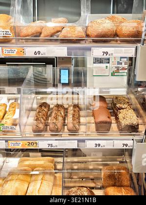 Kirov, Russia - 14 dicembre 2025: Gli articoli da forno sono ordinatamente disposti sugli scaffali di un negozio di alimentari. Sono disponibili diversi tipi di pane e panini Foto Stock
