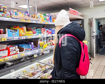 Kirov, Russia - 1 febbraio 2026: Un acquirente guarda le opzioni di spuntino in un corridoio del supermercato pieno di vetrine di prodotti colorati e molte scelte. Foto Stock