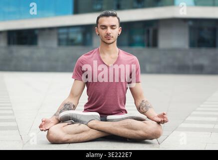 Bell'uomo che pratica yoga in posa di loto all'aperto Foto Stock