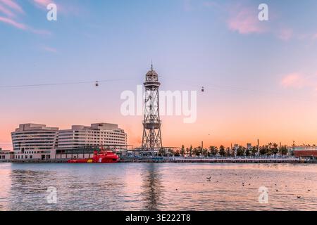 Tramonto rosa nel porto di Barcellona e la torre in acciaio Torre Jaume i della funivia Port Vell all'orizzonte, Spagna Foto Stock