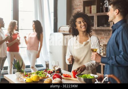 Una giovane coppia mista carina che prepara la cena in cucina Foto Stock