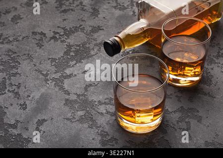 Due bicchieri di whisky e una bottiglia su fondo in marmo Foto Stock