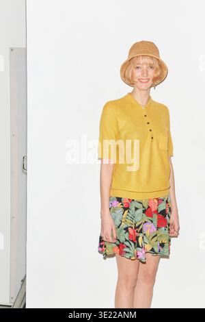 Donna sorridente con top giallo e gonna floreale che indossa un cappello di paglia su sfondo bianco. Germania Foto Stock