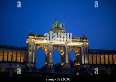 Monumento ad arco illuminato di notte contro un cielo blu profondo con colonnati circostanti. Bruxelles, Belgio Foto Stock