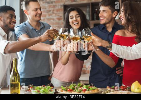 Amici felici che fanno il tifo con i bicchieri di vino bianco Foto Stock