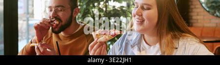 Giovane donna e giovane uomo che si godono la pizza insieme al chiuso Foto Stock