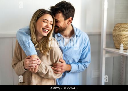 Coppia felice e variegata che condivide un momento di gioia a casa, abbracciando e sorridendo insieme Foto Stock