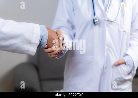 Primo piano di due medici che stringono la mano, simboleggiando la fiducia, il lavoro di squadra, la partnership professionale e la collaborazione nei servizi sanitari. Foto Stock