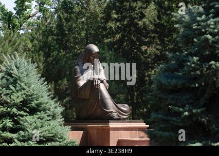 Tashkent (Toshkent), Uzbekistan (o'zbekiston) - 26 maggio 2025: Il monumento in bronzo della madre addolorata circondato da alberi sempreverdi nella Piazza della memoria, hono Foto Stock