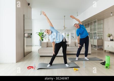 Allenamento fitness. Senior maturo sano in forma coppia che fa esercizio sportivo a casa. La moglie di mezza età ha un allenamento. Assistenza sanitaria stile di vita sano. Riabilitazione per anziani e donne Foto Stock
