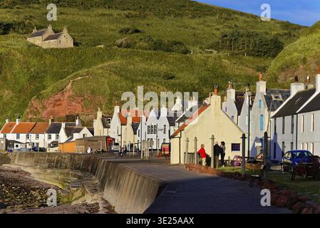Paesaggio costiero con case lungo scogliere sotto il cielo blu, villaggio di pescatori di Pennan sulla costa settentrionale scozzese, set del film LOCALE HERO With Foto Stock