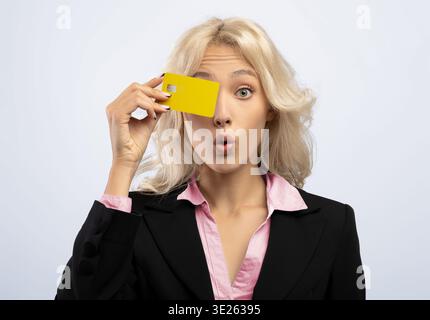 Donna che tiene il cartellino giallo per il viso in Studio Setting with Surprise Expression Foto Stock