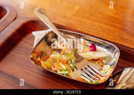 Presentazione Clean Meal. Piatto laterale non finito con frammenti e briciole di verdure su vassoio di legno Foto Stock
