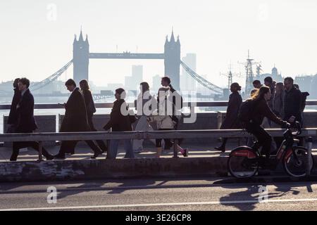 Pendolari e ciclisti attraversano il ponte di londra alla luce del mattino Foto Stock