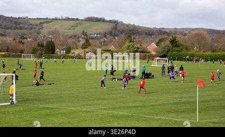 Bambini che giocano a football sul green Field durante gli eventi sportivi giovanili a Goring-on-Thames con sullo sfondo il Berkshire Downs Foto Stock