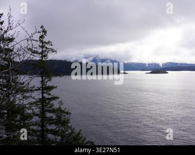 Le acque blu profonde di Howe Sound sono incorniciate da ripide montagne coperte di sempreverde e da una costa rocciosa sotto un cielo limpido nella Columbia Britannica Foto Stock