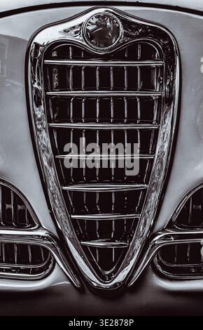 Primo piano della griglia di un'auto con cromo lucido sul cofano. Il grill è nero e argento. L'immagine ha un aspetto vintage. Foto Stock