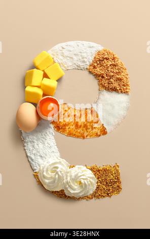 Lettera creativa a forma di e composta da ingredienti da forno come burro, uova, farina, zucchero e panna Foto Stock