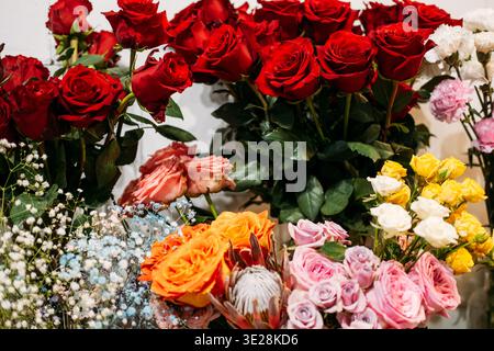 Vivaci mazzi di rose e fiori assortiti disposti in un negozio di fiori. Organizzazione dei fiori per la festa della mamma, fiori personalizzati. Foto Stock