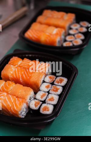 Scatola per sushi al salmone Readytoserve con rotoli e Maki ordinatamente disposti in vassoio nero, da asporto compatto Foto Stock