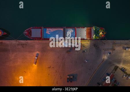 Veduta aerea di una grande nave da carico attraccata al porto, illuminata da luci calde e contrastanti contro le acque buie, vasto, Abruzzo, Italia. Foto Stock