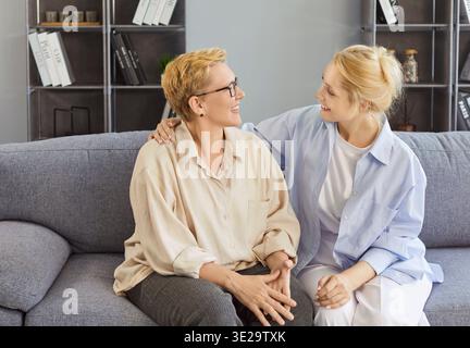 Madre anziana felice e figlia adulta vicino a casa seduto sul divano, donne amichevoli sorridono calorosamente Foto Stock