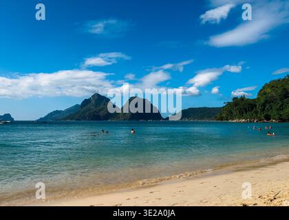 Vanilla Beach a El Nido, Palawan, Filippine, con nuotatori in calme acque turchesi e isole calcaree sotto un luminoso cielo tropicale. Foto Stock