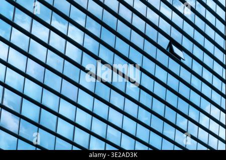 Milano, Lombardia, Italia - venerdì 13 2026: Facciata in vetro di un edificio moderno con un'unica finestra aperta e riflesso del cielo Foto Stock