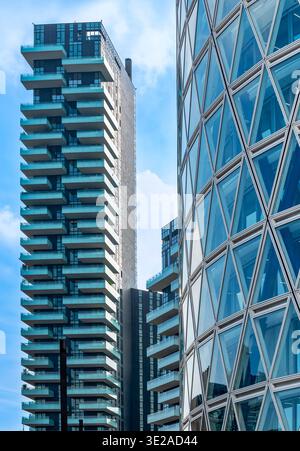 Milano, Lombardia, Italia - venerdì 13, 2026: Architettura moderna a Milano con balconi e una suggestiva facciata triangolare in vetro su un cielo blu Foto Stock