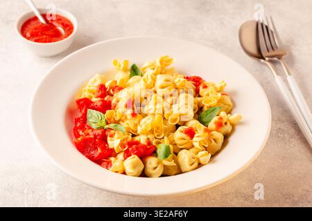 Pasta ripiena italiana. Sacсhettini pasta in un piatto con salsa di pomodoro. Foto Stock