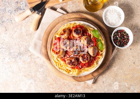 Un piatto di spaghetti classici conditi con polpette dorate e ricca salsa di pomodoro su un piatto di ceramica leggera. Foto Stock