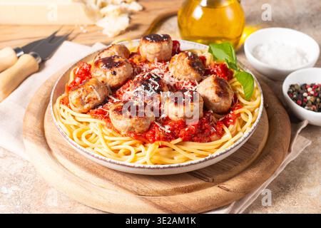 Un piatto di spaghetti classici conditi con polpette dorate e ricca salsa di pomodoro su un piatto di ceramica leggera. Foto Stock