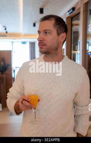 Uomo con succo d'arancia nella lounge dell'hotel boutique, Zermatt, Svizzera Foto Stock