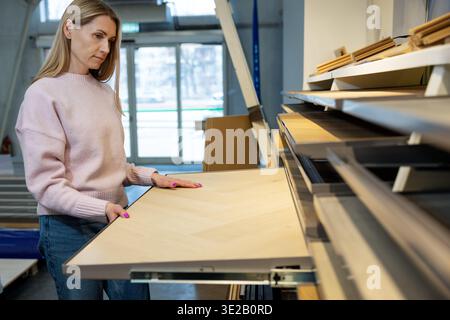 donna che sceglie mobili e materiali per pavimenti per la sua casa in un negozio di interior design Foto Stock