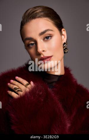 Una donna stupenda vestita con un lussuoso cappotto in pelliccia mette in mostra la sua bellezza ed eleganza con sicurezza. Foto Stock