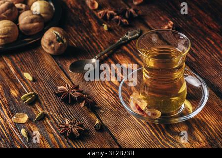 Cibo, tè speziato con anice stellato, cardamomo e calce secca in vetro armudu su una superficie in legno Foto Stock
