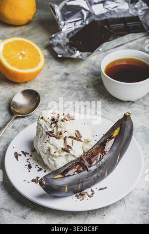 Cibo, dolce dolce. Banana grigliata con cioccolato fondente, succo di agrumi e gelato alla vaniglia Foto Stock